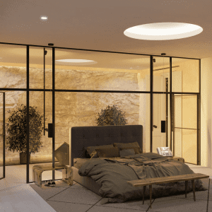Habitación con banqueta al pie de la cama y jardín interior con roca natural en la Escuela de Diseño de Madrid: un oasis de serenidad y belleza natural.